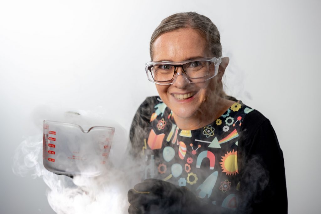 Jenny Lynch holding a jug of liquid nitrogen surrounded by clouds of water vapour